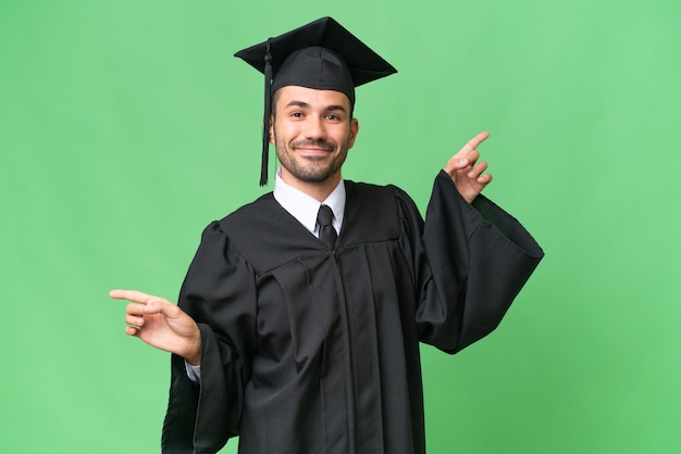 Young university graduate man over isolated background pointing finger to the laterals and happy