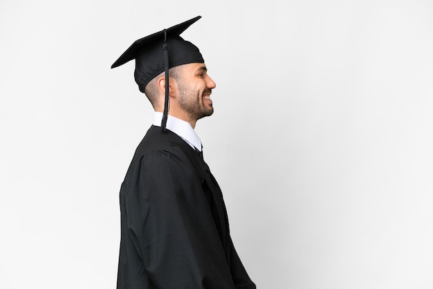 Young university graduate man over isolated white background in lateral position