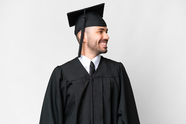 Young university graduate man over isolated white background looking side