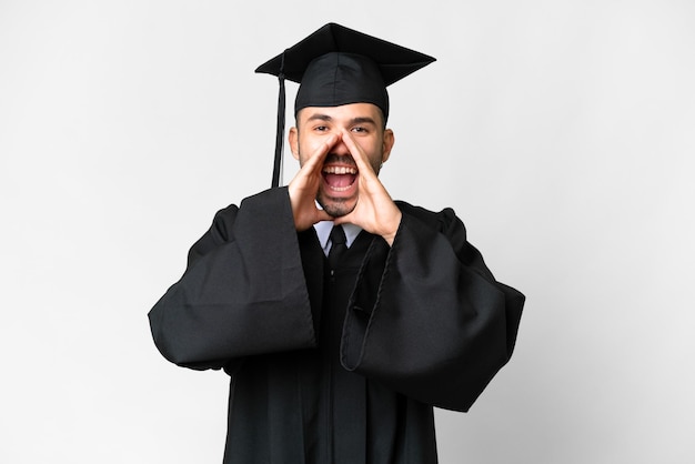 Young university graduate man over isolated white background shouting and announcing something