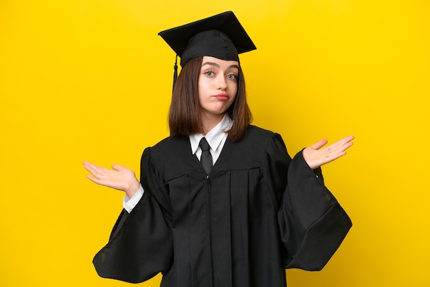 Young university graduate Ukrainian woman isolated on yellow background having doubts while raising hands