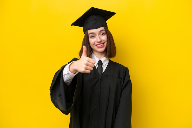 Young university graduate ukrainian woman isolated on yellow background with thumbs up because something good has happened