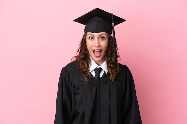 Giovane donna laureata isolata su sfondo rosa con espressione facciale a sorpresa