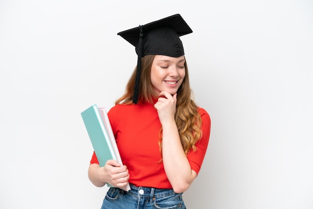 Young university graduate woman isolated on white background looking to the side and smiling