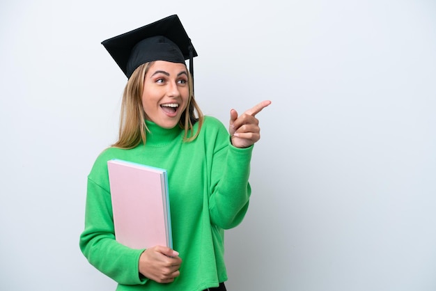 Young university graduate woman isolated on white background\
pointing finger to the side and presenting a product