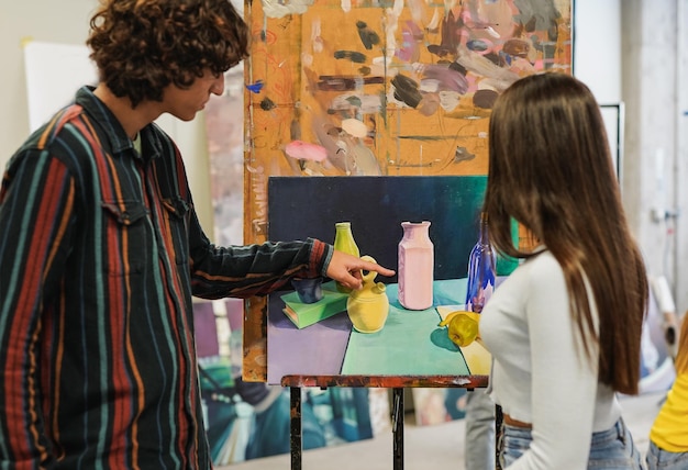 Young university students painting inside art classroom