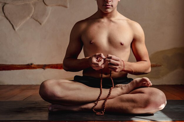 Young unrecognizable man meditating with a rudraksha mala in his hands