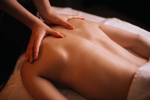 Young unrecognizable woman gets professional back massage in spa salon