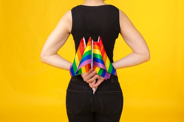 Молодая неузнаваемая женщина держит маленький флаг ЛГБТ