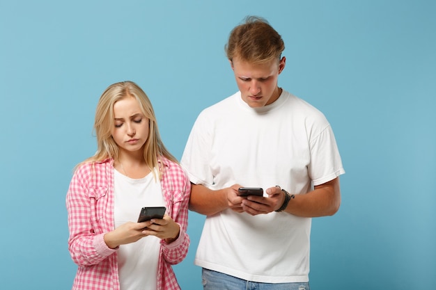 Young upset couple friends man and woman  in white pink empty blank t-shirts posing 