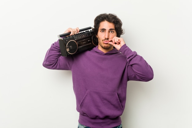 Young urban man holding a guetto blaster with fingers on lips keeping a secret.