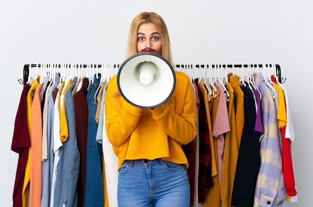 Young Uruguayan blonde woman in a clothing store shouting through a megaphone