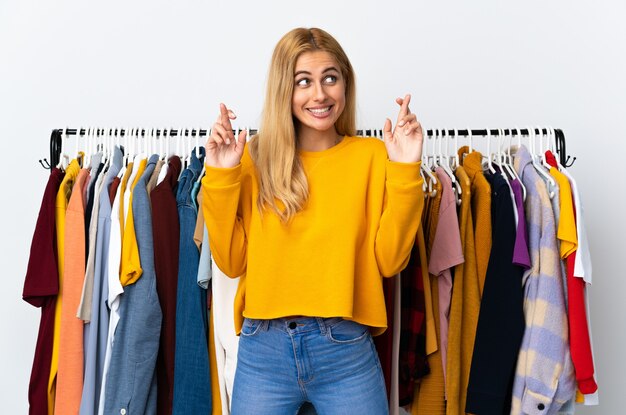 Young Uruguayan blonde woman in a clothing store with fingers crossing