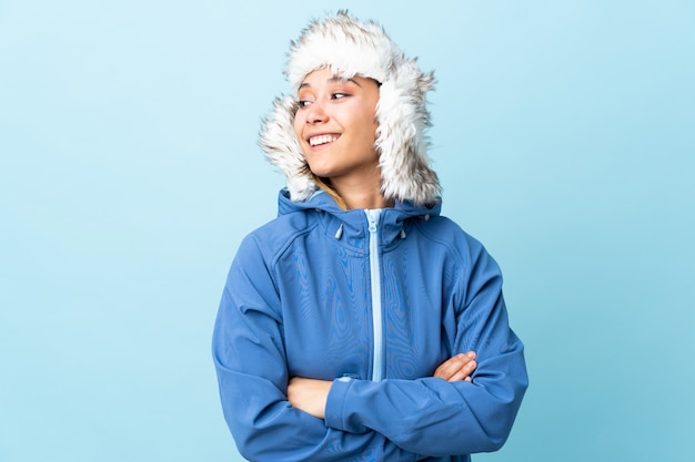 Young Uruguayan girl with winter hat isolated on blue laughing