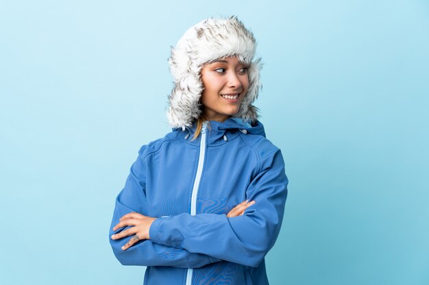 Young Uruguayan girl with winter hat isolated on blue wall looking to the side