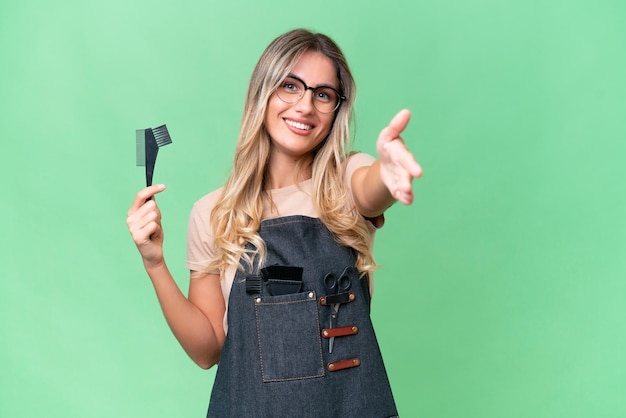 Young Uruguayan hairdresser woman over isolated background shaking hands for closing a good deal