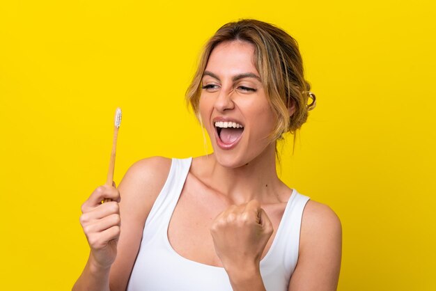 Young Uruguayan woman brushing teeth isolated on yellow background celebrating a victory