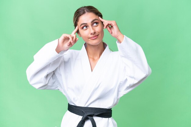 Young Uruguayan woman doing karate over isolated background having doubts and thinking