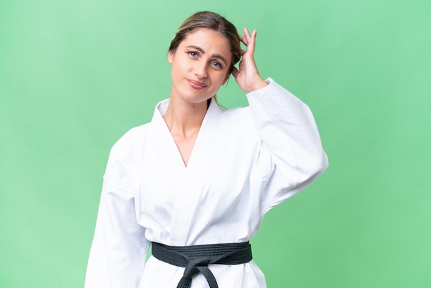 Young Uruguayan woman doing karate over isolated background having doubts