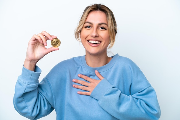 Photo young uruguayan woman holding a bitcoin isolated on white background smiling a lot