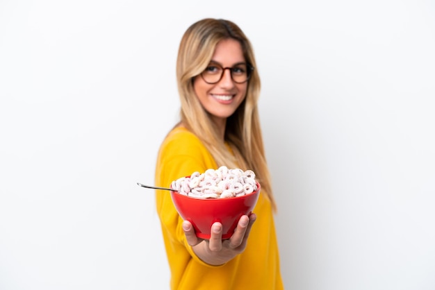 Young Uruguayan woman holding a bowl of cereals isolated on white background with happy expression