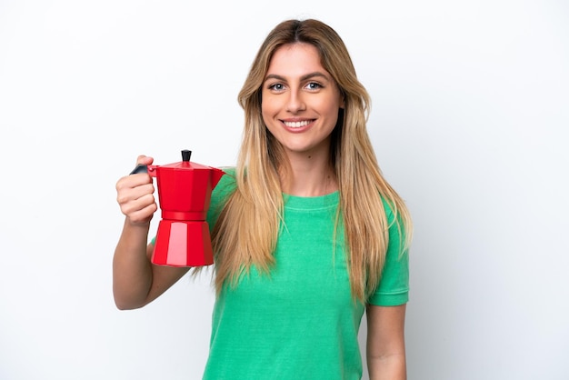 Young Uruguayan woman holding coffee pot isolated on white background smiling a lot