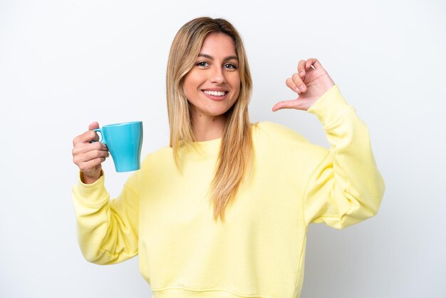 Young Uruguayan woman holding cup of coffee isolated on white background proud and selfsatisfied