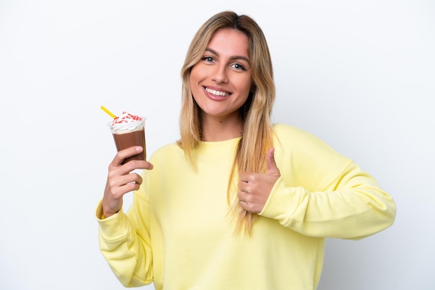 Young Uruguayan woman holding Frappuccino isolated on white background giving a thumbs up gesture