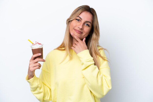 Young Uruguayan woman holding Frappuccino isolated on white background happy and smiling