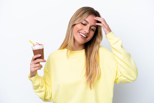 Young Uruguayan woman holding Frappuccino isolated on white background laughing