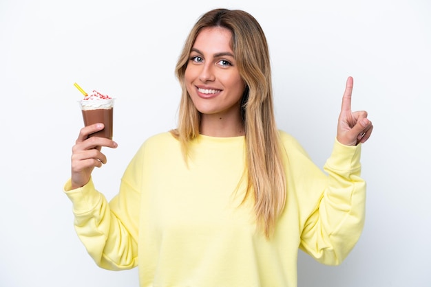 Young Uruguayan woman holding Frappuccino isolated on white background pointing up a great idea