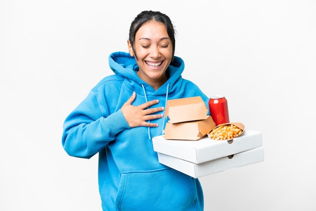 写真 たくさんの笑顔を浮かべて孤立した白い背景の上にピザとハンバーガーを保持している若いウルグアイ人女性