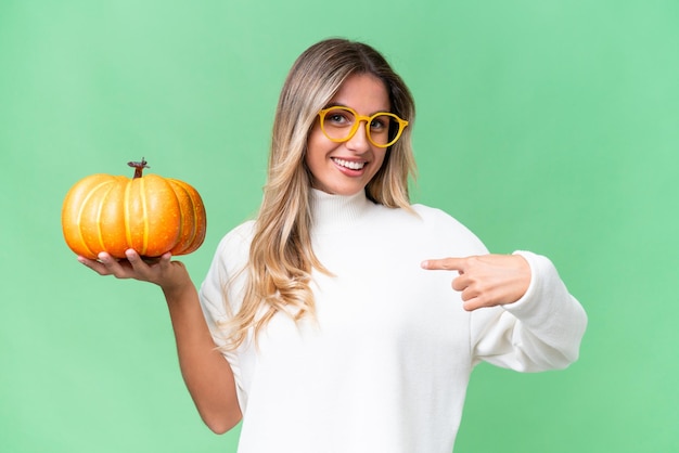 Young Uruguayan woman holding a pumpkin over isolated background with surprise facial expression