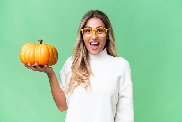 Young Uruguayan woman holding a pumpkin over isolated background with surprise and shocked facial expression