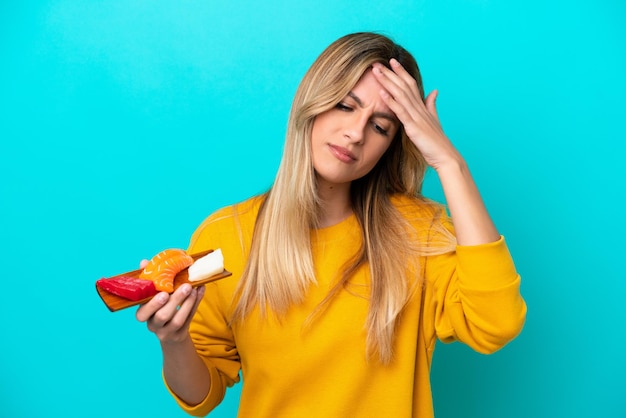 Young Uruguayan woman holding sashimi isolated on blue background with headache