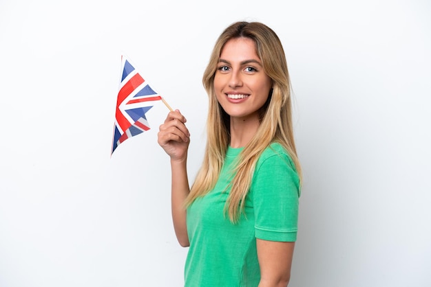 Young Uruguayan woman holding an United Kingdom flag isolated on white background smiling a lot