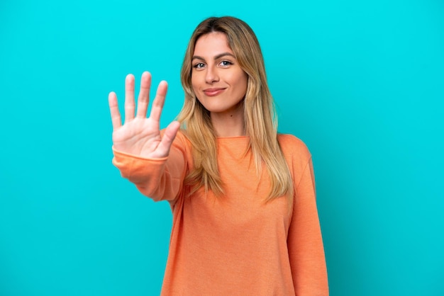 Young Uruguayan woman isolated on blue background counting five with fingers