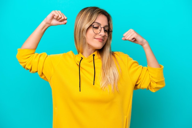 Young Uruguayan woman isolated on blue background doing strong gesture