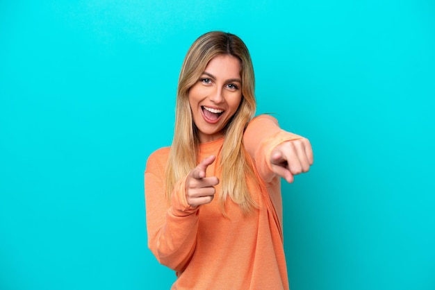 Young Uruguayan woman isolated on blue background pointing to the front and smiling