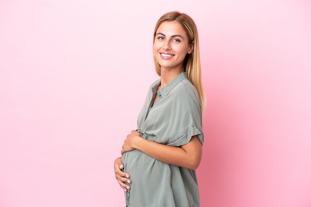 Young Uruguayan woman isolated on blue background pregnant and happy