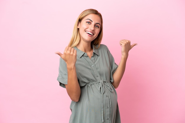 Young Uruguayan woman isolated on blue background pregnant and with thumb up