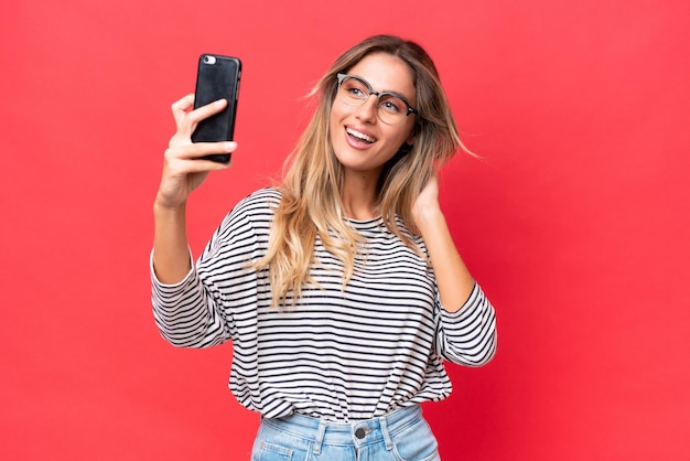 young uruguayan woman isolated on red background making a selfie