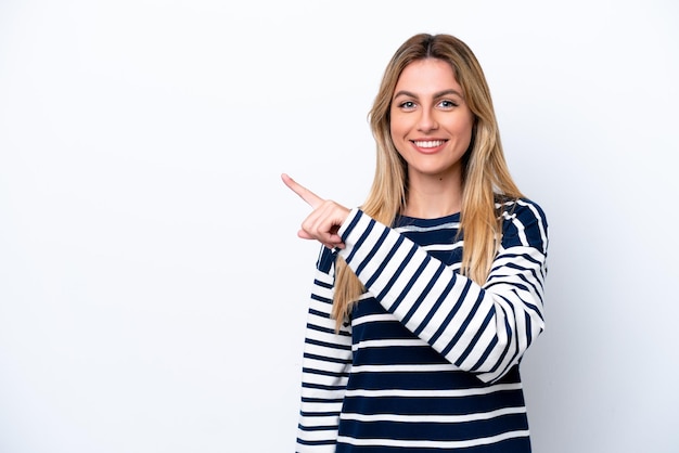 Foto giovane donna uruguaiana isolata su sfondo bianco che indica il lato per presentare un prodotto