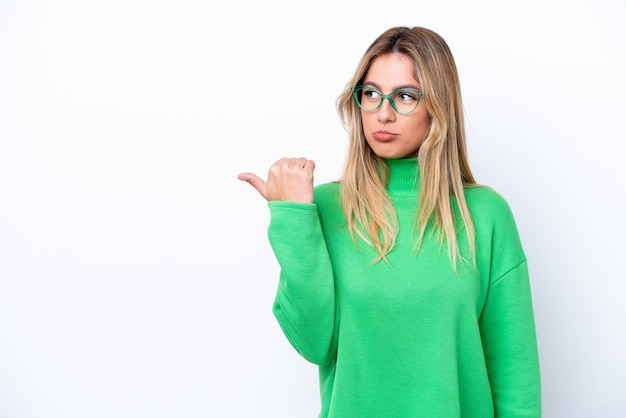 Young Uruguayan woman isolated on white background unhappy and pointing to the side