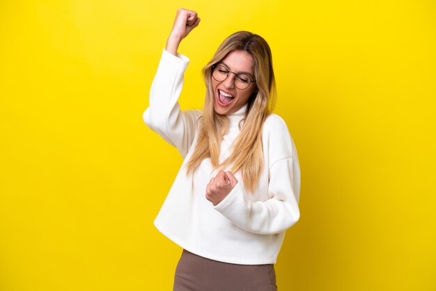 Young uruguayan woman isolated on yellow background celebrating a victory