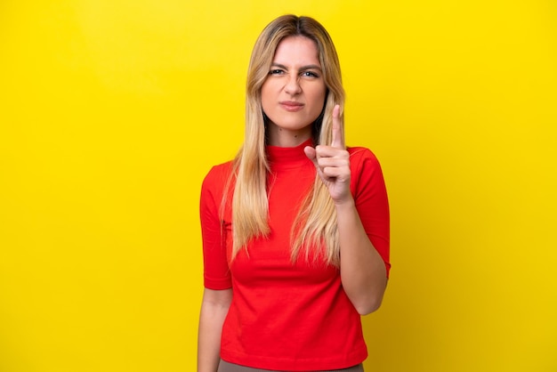 Young uruguayan woman isolated on yellow background frustrated and pointing to the front