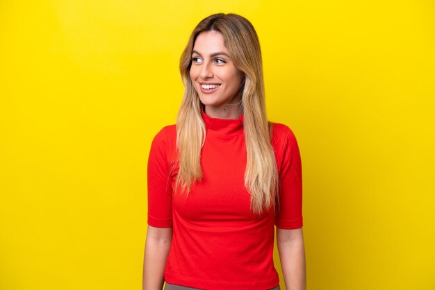 Young Uruguayan woman isolated on yellow background looking side