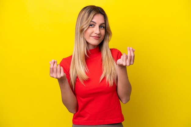 Young Uruguayan woman isolated on yellow background making money gesture