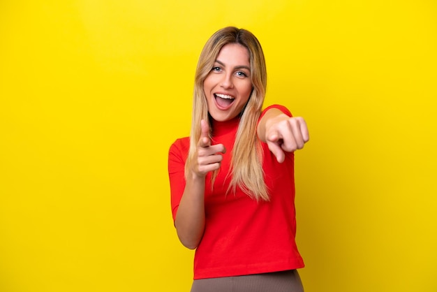 Young Uruguayan woman isolated on yellow background pointing to the front and smiling