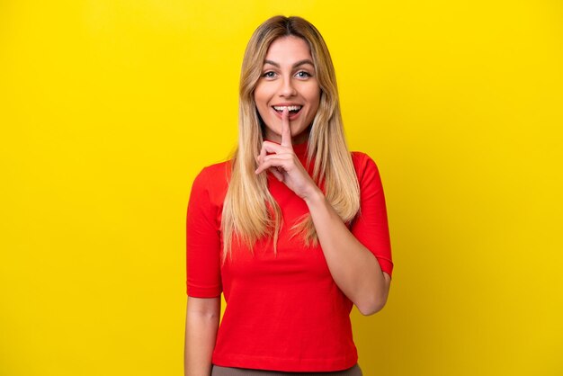 Young uruguayan woman isolated on yellow background showing a sign of silence gesture putting finger in mouth